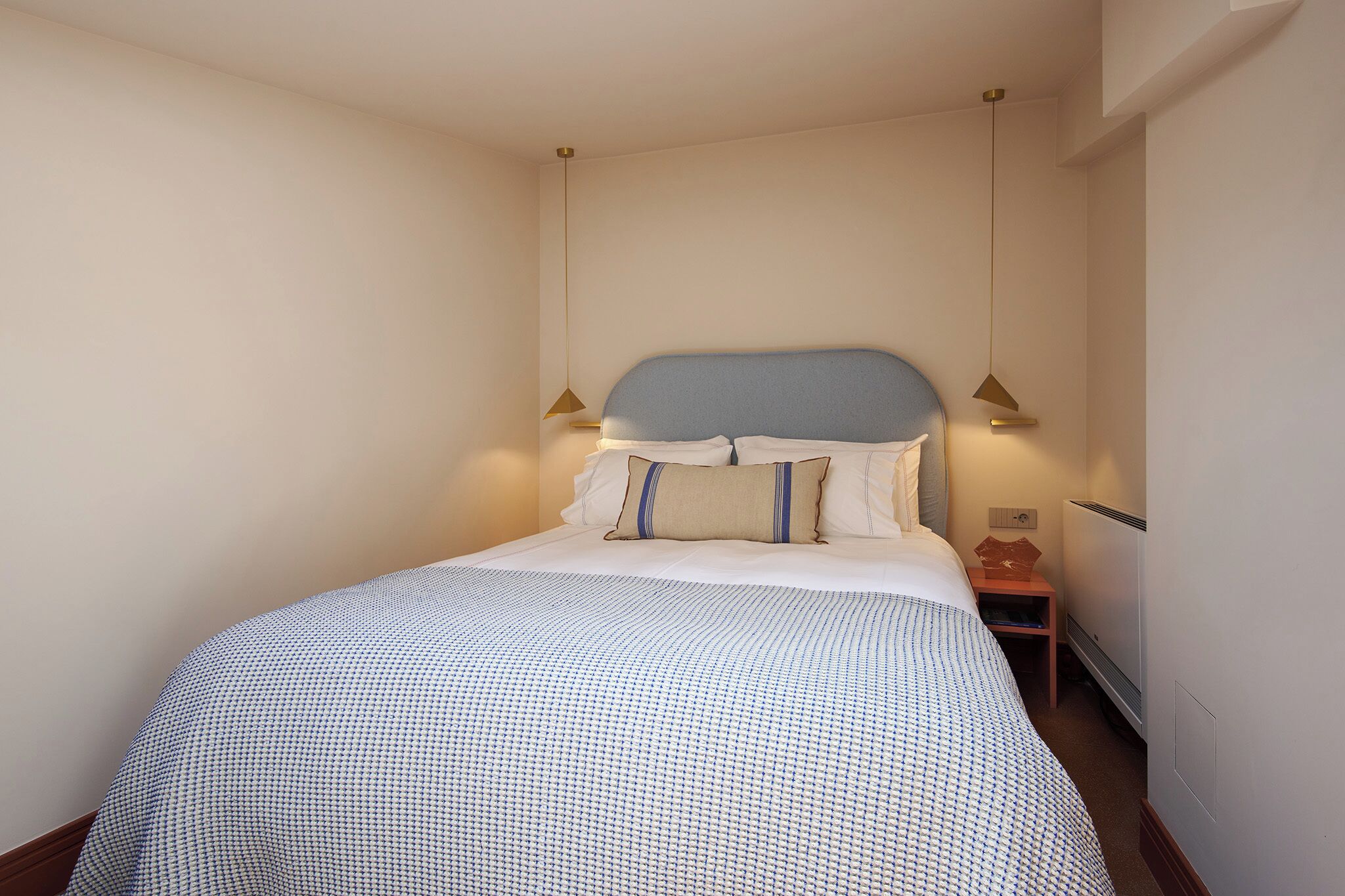 A neatly made bed with a patterned bedspread, a headboard, and two bedside lamps.