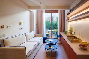 A modern living room with a sofa, a coffee table, and a kitchen area with a sink and shelves. - Loom Athens (Athens)