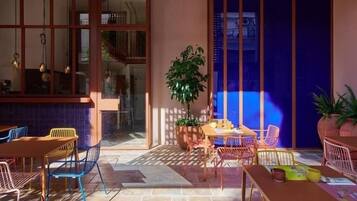 Un patio al aire libre con una mesa y sillas de madera, una planta en maceta y vista a un edificio a través de un ventanal.