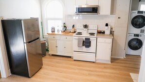 Una cocina moderna con electrodomésticos de acero inoxidable, armarios blancos y horno empotrado.