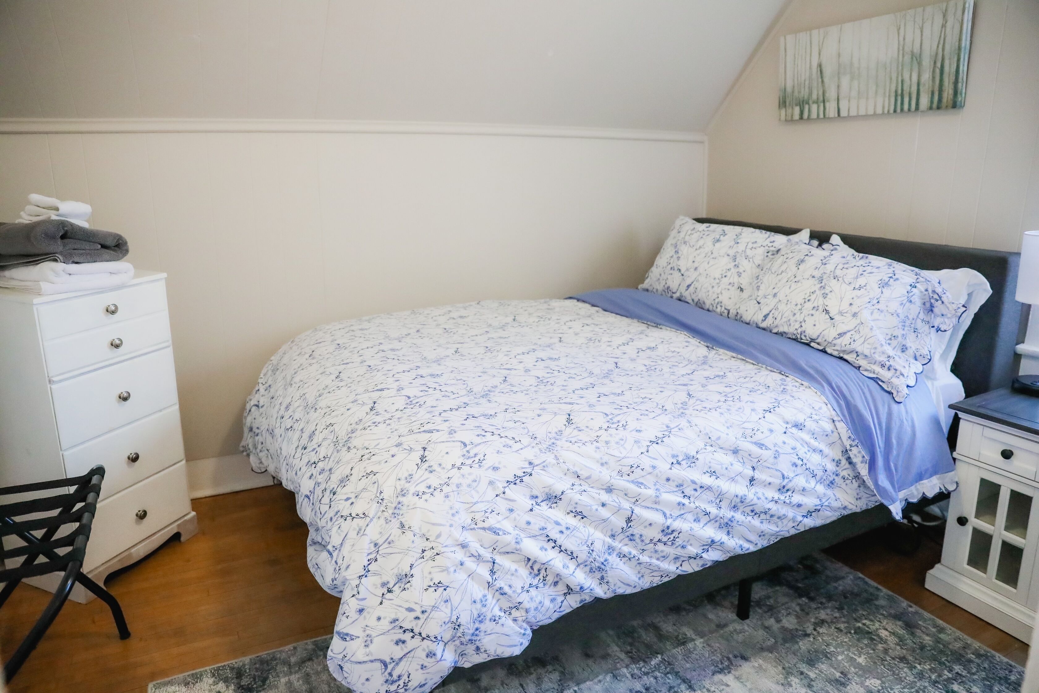 A bedroom with a bed, a dresser, a chair, and a nightstand.