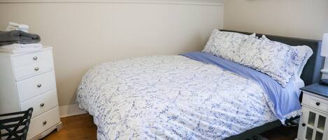 A bedroom with a bed, a dresser, a chair, and a nightstand.