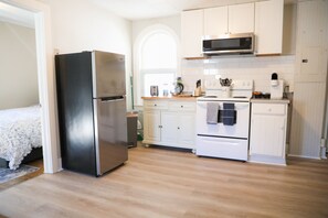 Una cocina moderna con electrodomésticos de acero inoxidable, armarios blancos y encimera de madera.