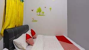 A bedroom with a bed, a headboard, a curtain, and wall decorations. - Hotel O Hasan House Syariah 2NearVihara Budhi Bhakti (Batam)