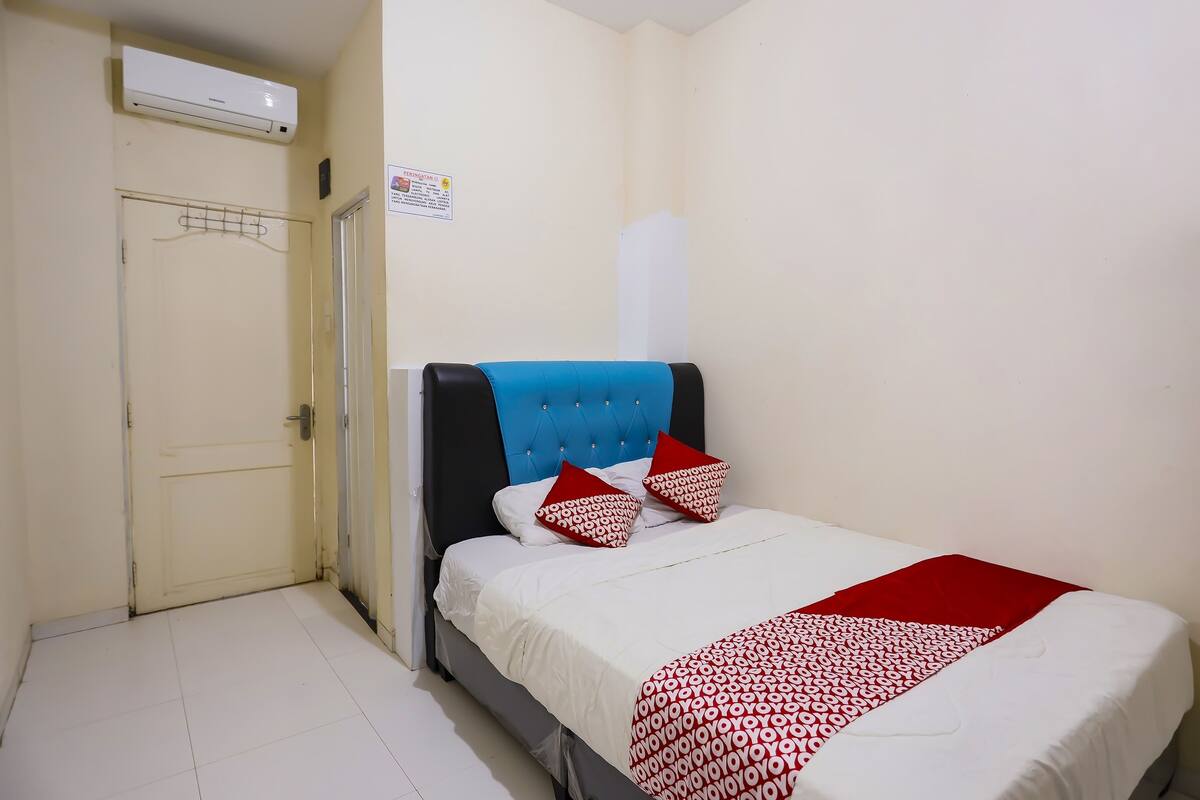 A hotel room with a bed, a wardrobe, and an air conditioning unit.
