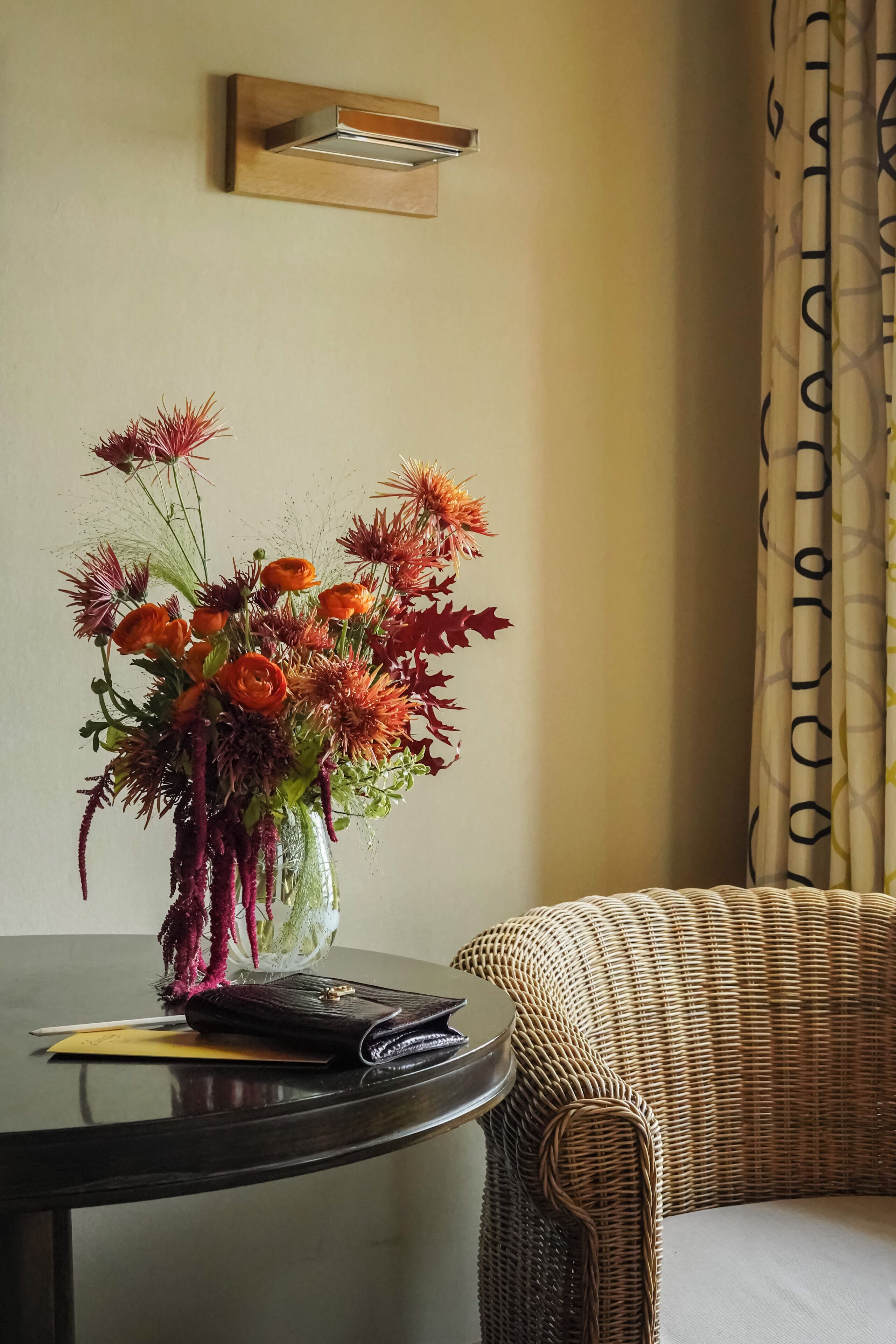 A round table with a vase of flowers and a wallet.