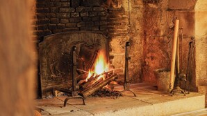 A fireplace with a fire, a stone wall, and a wooden bench. - L'Absinthe Hôtel (Honfleur)