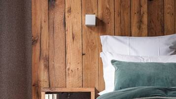 Een houten hoofdbord met een plank, witte beddengoed en een groen kussen.