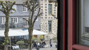 A courtyard with outdoor seating, a dog, and a building with a stone facade. - L'Absinthe Hôtel (Honfleur)