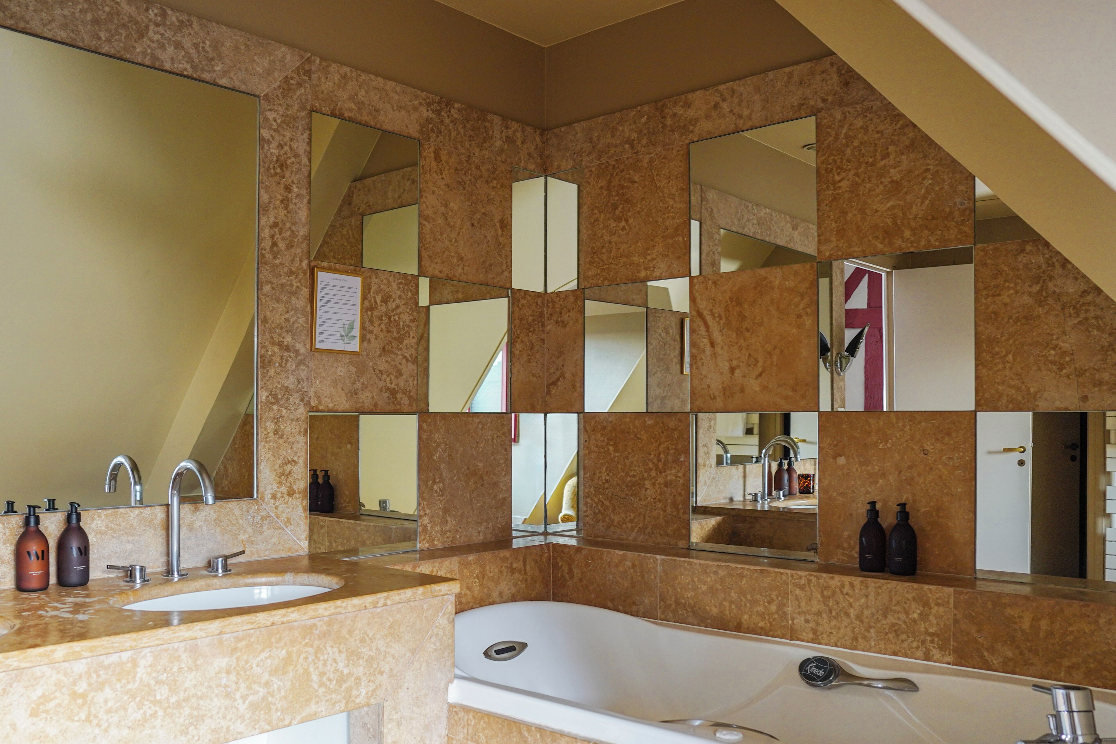 Une salle de bain avec un double lavabo, une baignoire et plusieurs miroirs.