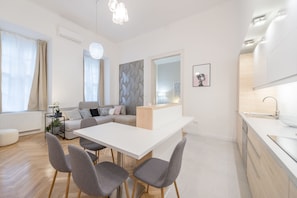 A modern living space with a dining area, kitchen, and seating area.