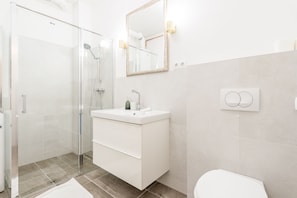 A modern bathroom with a glass shower enclosure, a white vanity with a mirror, and a toilet.