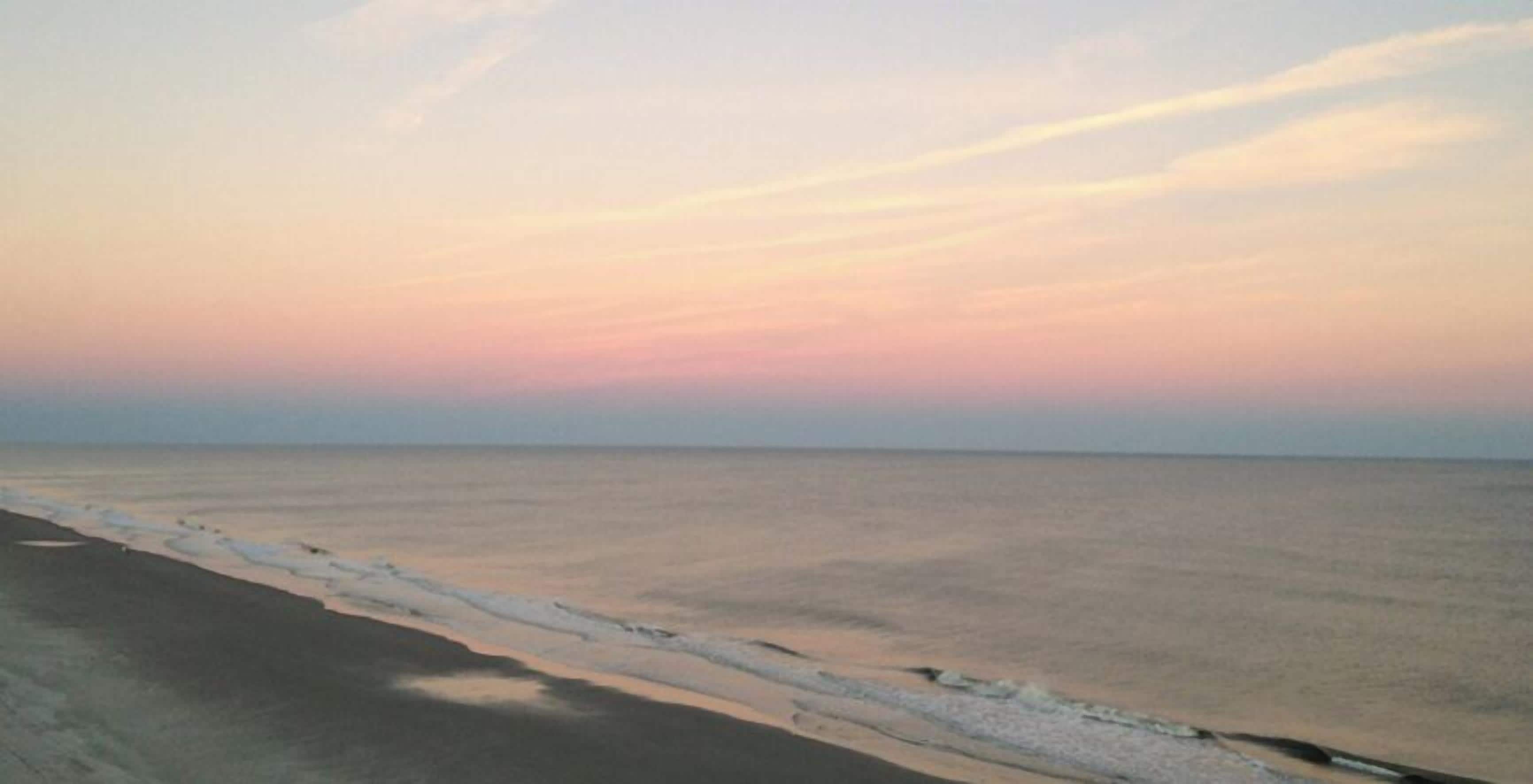 Ein Strand mit blauem Himmel und ruhiger See.