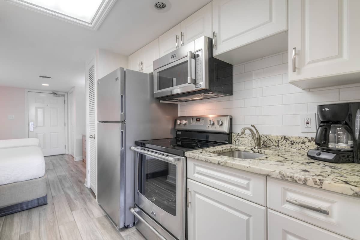 A modern kitchen with stainless steel appliances, white cabinetry, and a granite countertop.