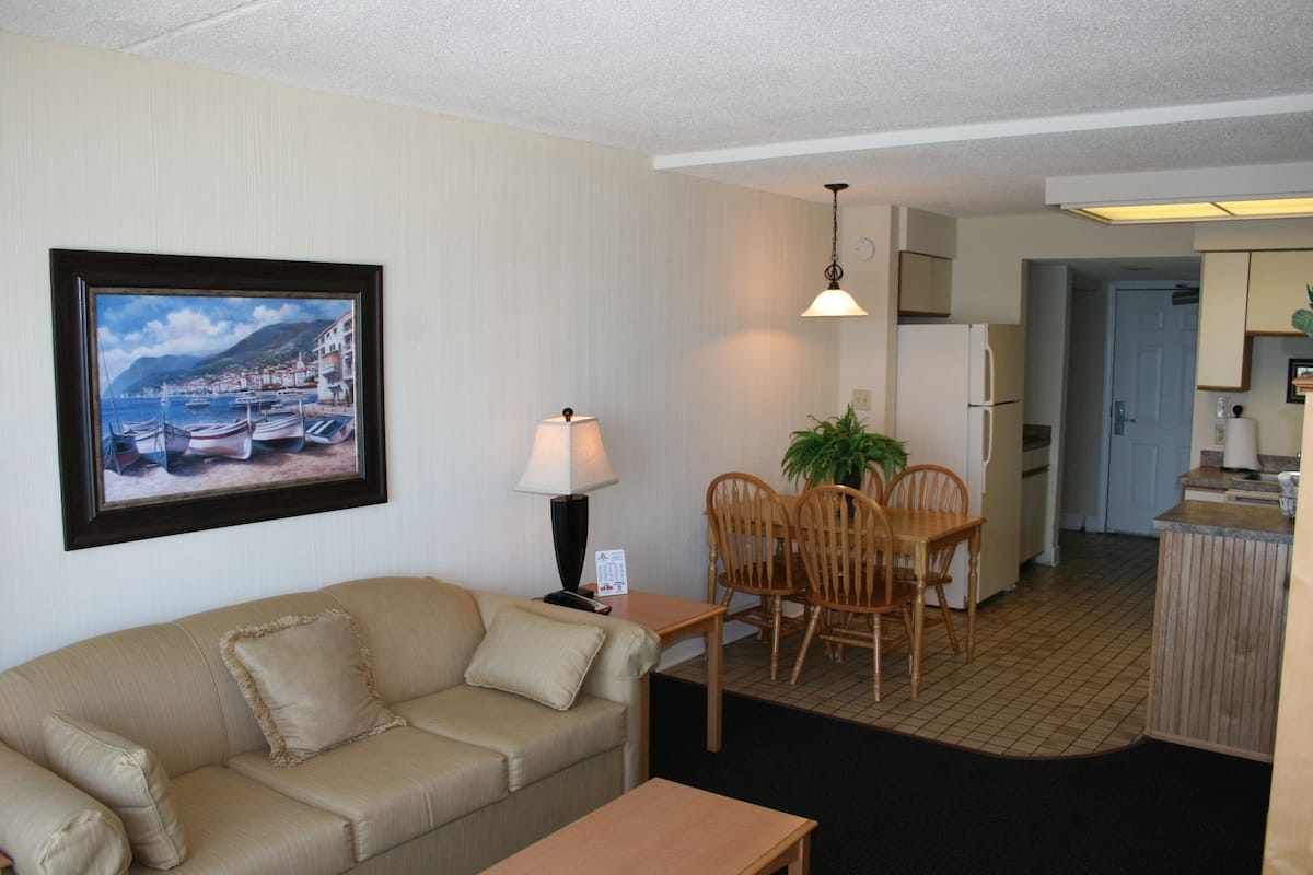 A compact living space with a sofa, dining table, chairs, and a kitchen area.