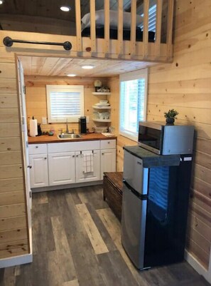 Cozy cabin kitchen with a sink, stove, and refrigerator, offering a convenient space for meal preparation.