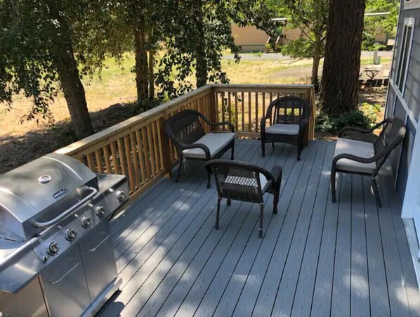 Enjoy al fresco dining and socializing on this outdoor deck with barbecue grill, comfortable seating for two, and a small table.