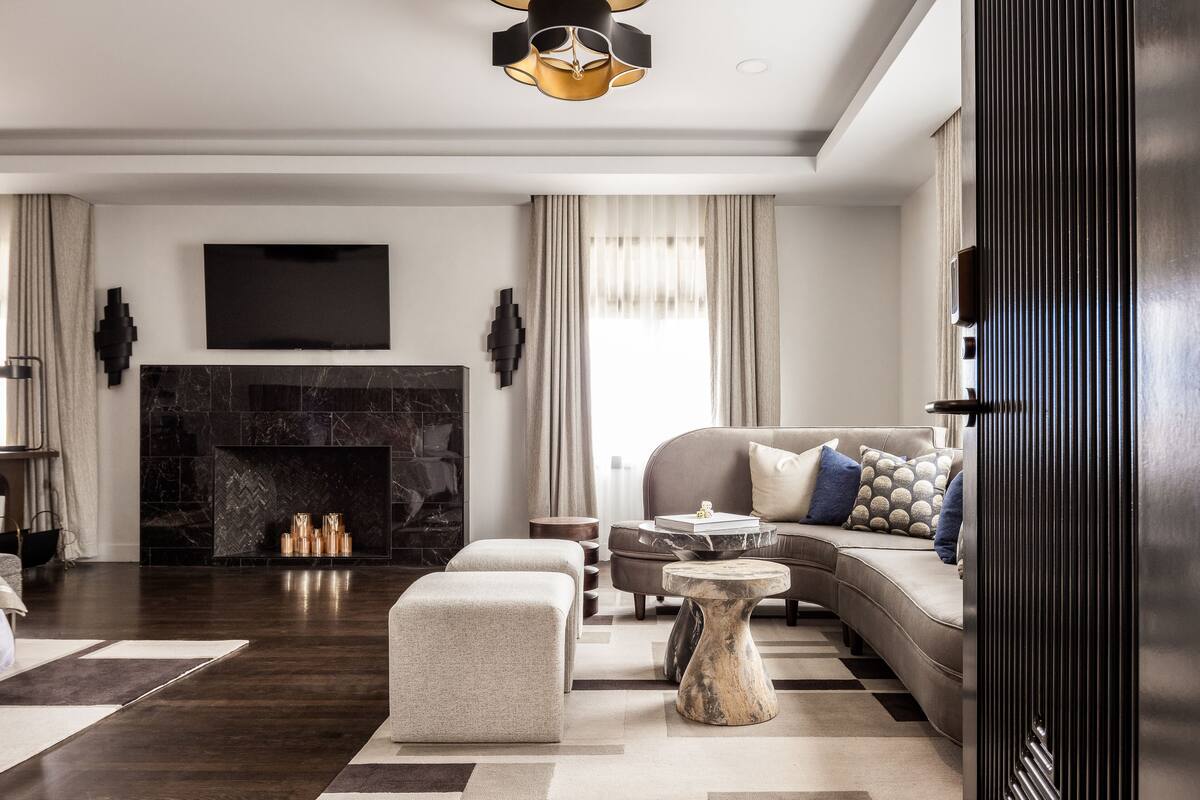 A modern living room with a fireplace, a sofa set, a coffee table, and a television mounted on the wall.