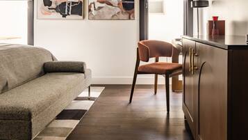 A modern living room with a sofa, a chair, a cabinet, and abstract art on the wall.