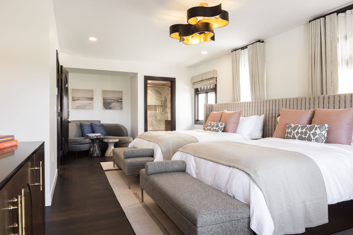 A modern hotel room with a large bed, two bedside tables, a sofa, and a desk.