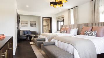 A modern hotel room with a large bed, two bedside tables, a sofa, and a desk.