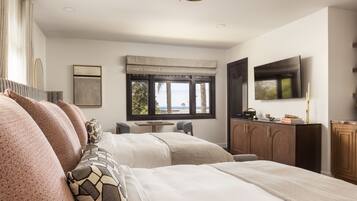 Habitación de hotel moderna con dos camas, televisión, escritorio y vistas al exterior.