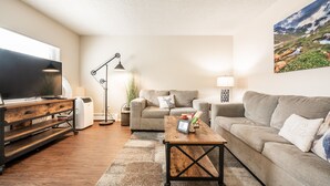 A living room with a large flat-screen TV, two sofas, a coffee table, and a floor lamp. - ❤Cozy in the Springs! 2 BR, Kitchen. 4 Guests!❤ (Colorado Springs)