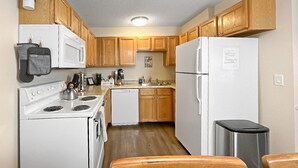 Une cuisine de taille réduite, dotée de meubles en bois, d’une cuisinière blanche, d’un lave-vaisselle et d’un réfrigérateur.
