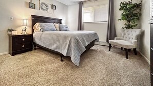 A bedroom with a bed, a nightstand, a chair, a potted plant, and a window with blinds. - Beauty in the Springs"Entire Condo Great Location (Colorado Springs)