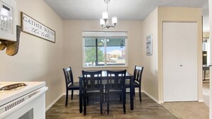 A dining area with a table and chairs, a window with blinds, a chandelier, and a sign on the wall. - Beauty in the Springs"Entire Condo Great Location (Colorado Springs)