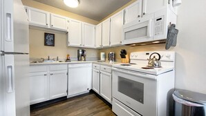 A kitchen with white cabinets, a microwave, a stove, and a coffee maker. - ★Academy Hideaway With View! Sleeps 4 with AC!★ (Colorado Springs)