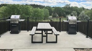 En uteplats med två grillar och ett picknickbord.