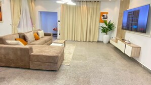 A modern living room with a sectional sofa, a flat-screen TV, and a minimalist design. - TAOhomes (Abuja)
