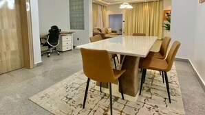 A modern dining area with a large rectangular table, multiple chairs, and a unique ceiling light fixture. - TAOhomes (Abuja)