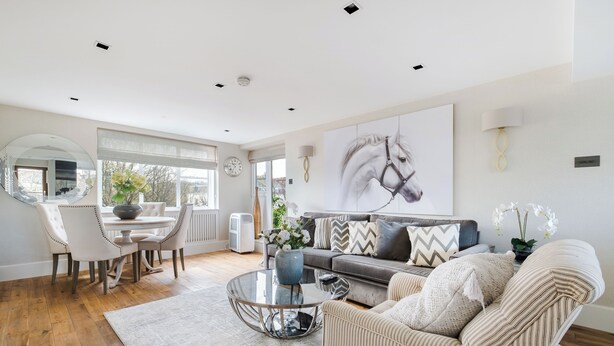 A modern living room with a sofa, armchair, and coffee table. There is a dining area with a table and chairs. A large painting of a horse is on the wall. -  LONDONERS│Magnificent Londoner  (London)