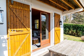 A wooden door with a glass panel, a wooden bench, and a garden view.