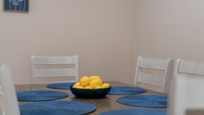 A dining table with a bowl of lemons, blue placemats, and white chairs. - Large spacious Home (Enterprise)
