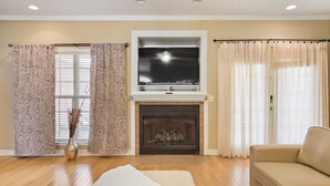 A living room with a fireplace, a sofa, and curtains. - Large spacious Home (Enterprise)