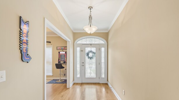 A hallway with a chandelier, a door with a wreath, and a neon sign. - Large spacious Home (Enterprise)