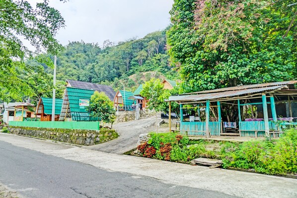 Uma aldeia rural com casas tradicionais, uma estrada pavimentada e vegetação exuberante.