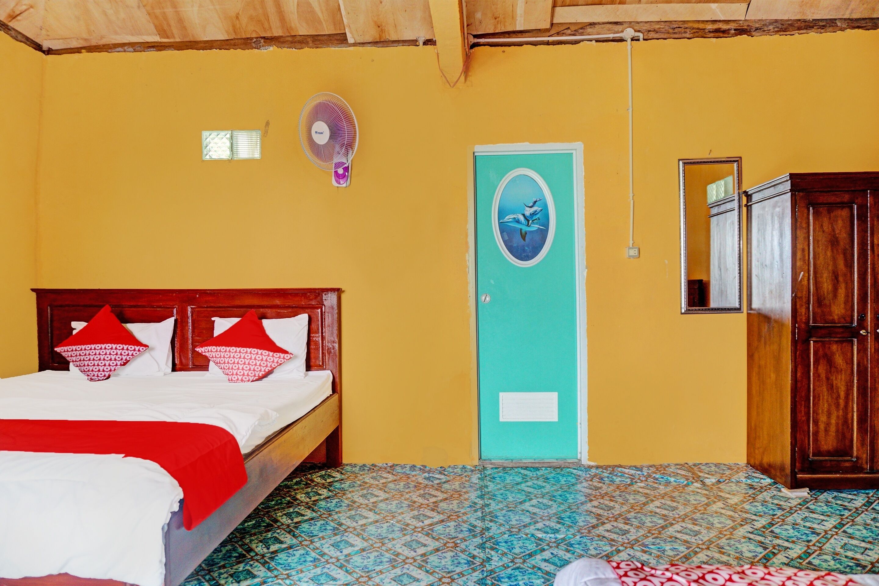 Een kamer met een bed, een ventilator, een deur met een vogelstickers en een kledingkast.