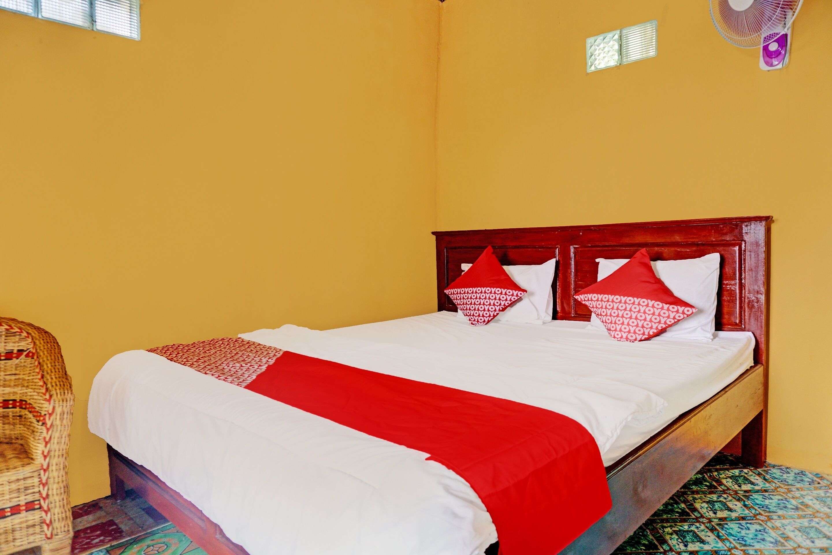 A bed with a wooden headboard, white and red bedding, and a red throw blanket.