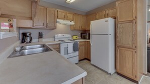 A kitchen with wooden cabinets, a white refrigerator, a stove, and a sink. - FALOLA ESTATES: Live in heaven on earth in our beautiful home (Indianapolis)
