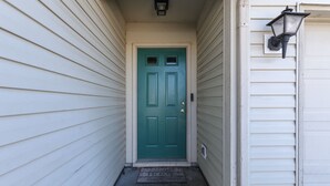 A narrow entrance with a green door, a small step, and a 'HOME' mat. - FALOLA ESTATES: Live in heaven on earth in our beautiful home (Indianapolis)
