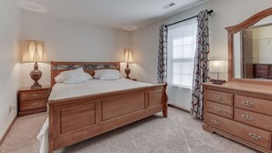 A bedroom with a wooden bed, two bedside tables with lamps, a dresser, and a mirror. - FALOLA ESTATES: Live in heaven on earth in our beautiful home (Indianapolis)