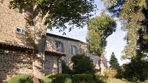 Ein Steinhaus mit Ziegeldach, einem kleinen Fenster und einer Bank im Vordergrund.