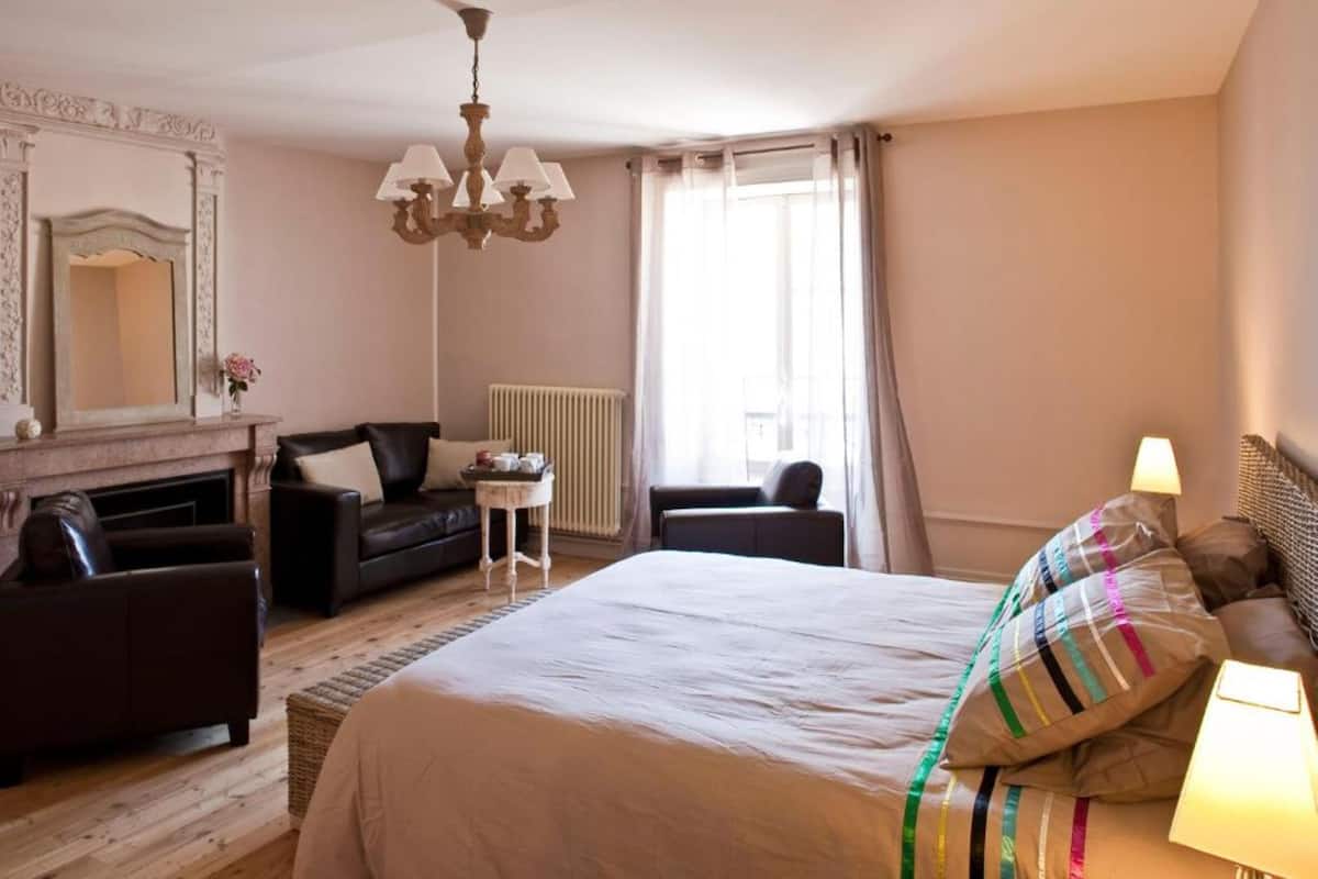 Een hotelkamer met een groot bed, twee sofa's, een klein tafeltje, een radiator en een kroonluchter.