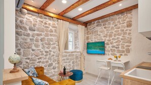 Una habitación acogedora con pared de piedra, techo de madera, un sofá, una mesita y un cuadro.