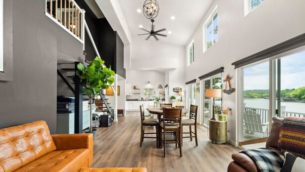 A spacious living area with a dining table, sofas, and a staircase leading to an upper level.