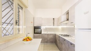 Una cocina moderna con encimera blanca, armarios grises, horno empotrado y estufa a gas.